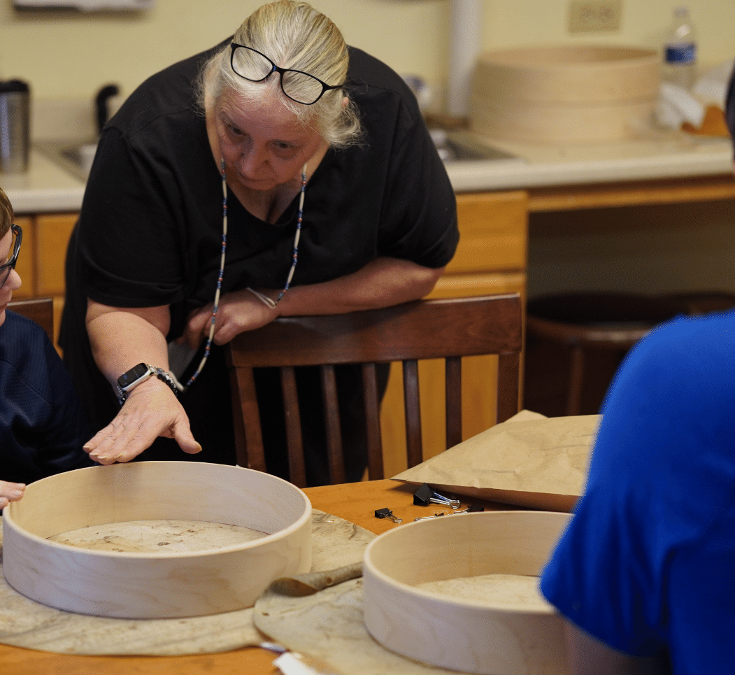 Educator assisting a child during a drum making workshop.